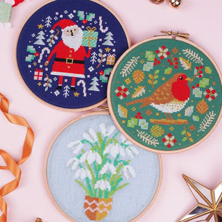 Christmas themed cross stitch patterns displayed in hoops