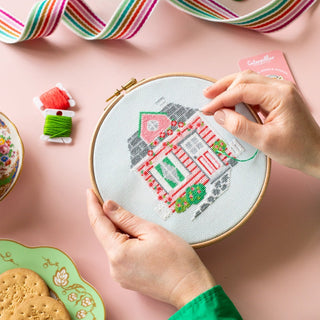 Person stitching pink cottage cross stitch pattern