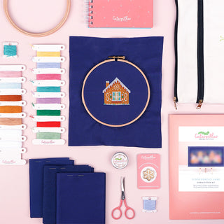 Gingerbread Lane Stitch-a-long flat lay with needle minder, thread wax, scissors, hoop and project bag