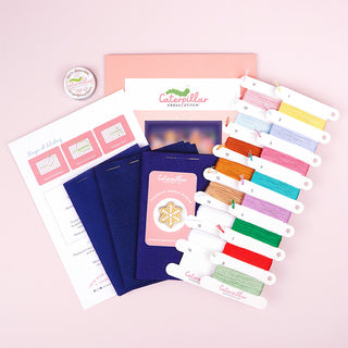 Gingerbread Lane Stitch-a-long standard kit supplies showing three fabric options, thread wax and gingerbread cookie needle minder