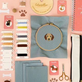 Dog themed cross stitch pattern in embroidery hoop with accessories and supplies