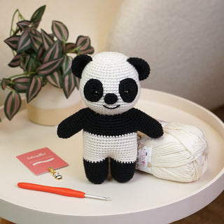 Poppy the Panda finished project stood next to yarn, hook and stitch marker