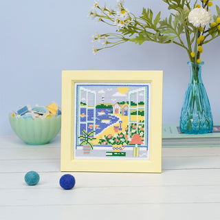 Summer View stitched sample in frame on table with accessories