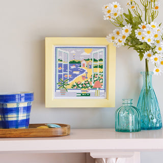 Summer View stitched sample in yellow frame hanging on wall